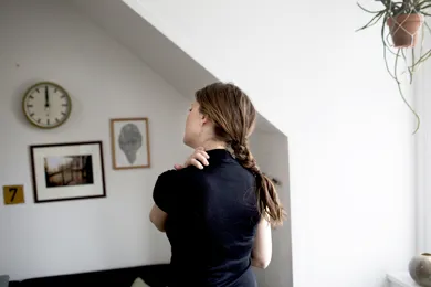 Kvinde holder sin haand paa nakken paa grund af smerter.