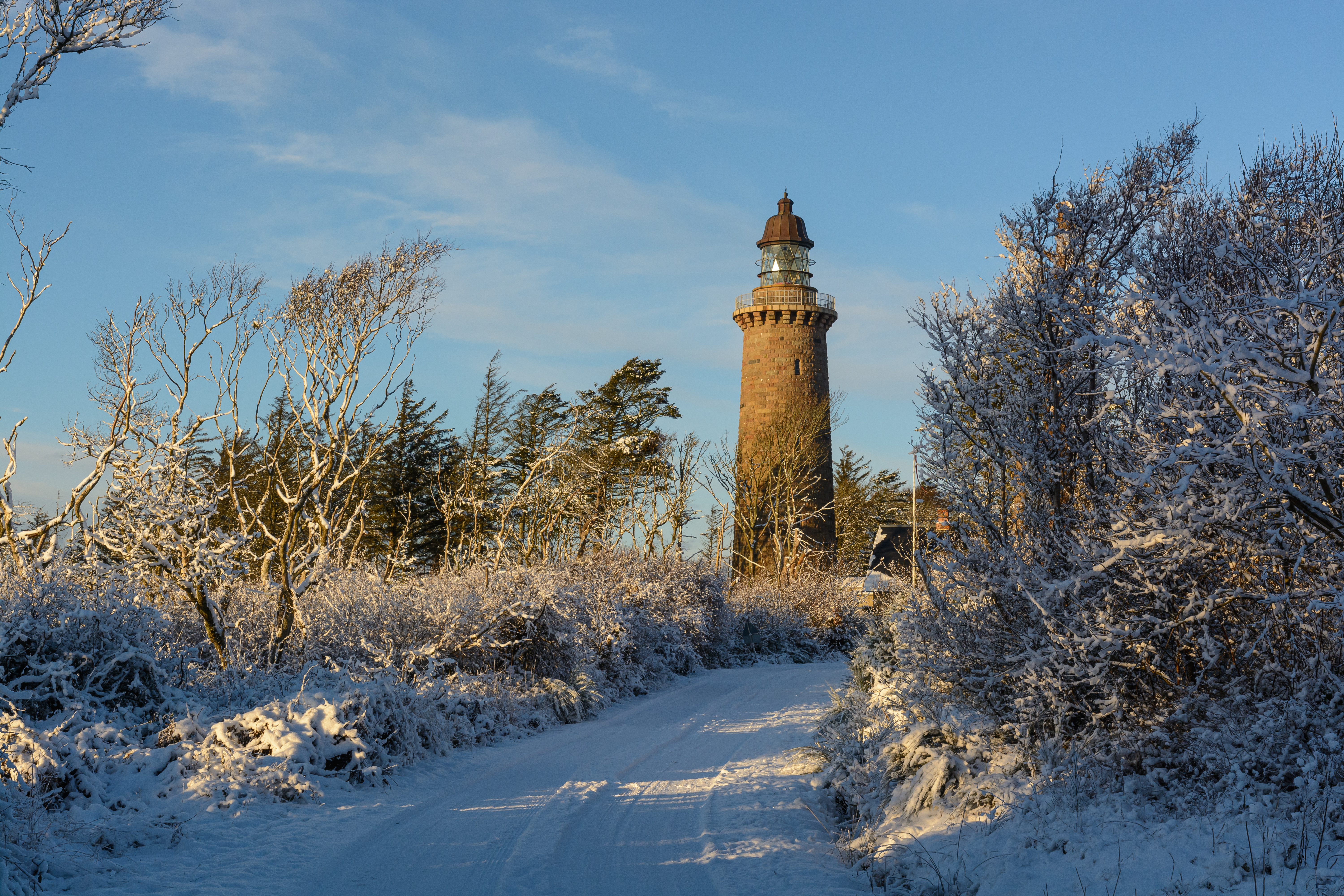 Snedækket sti med fyrtårn i baggrunden