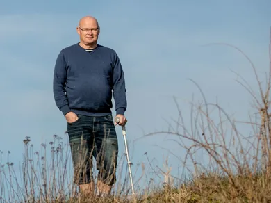 Dan Rahbaek gaar med en krykke ved vandet