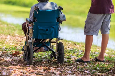 En person i koerestol sidder ved siden af en staaende person