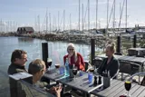 Fire personer sidder og snakker ved havnen i Dragør.