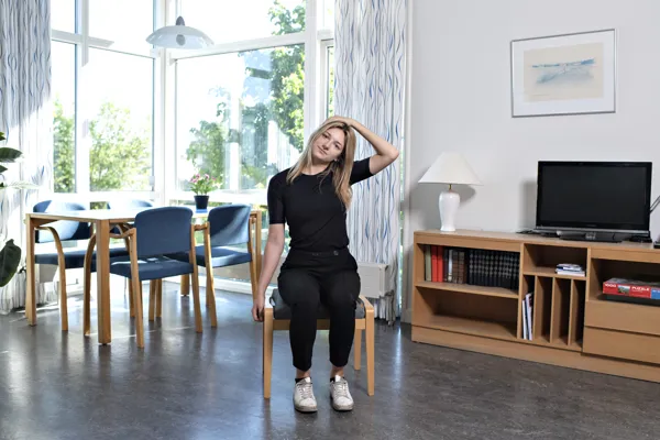 En kvinde udfører nakkeøvelser siddende.