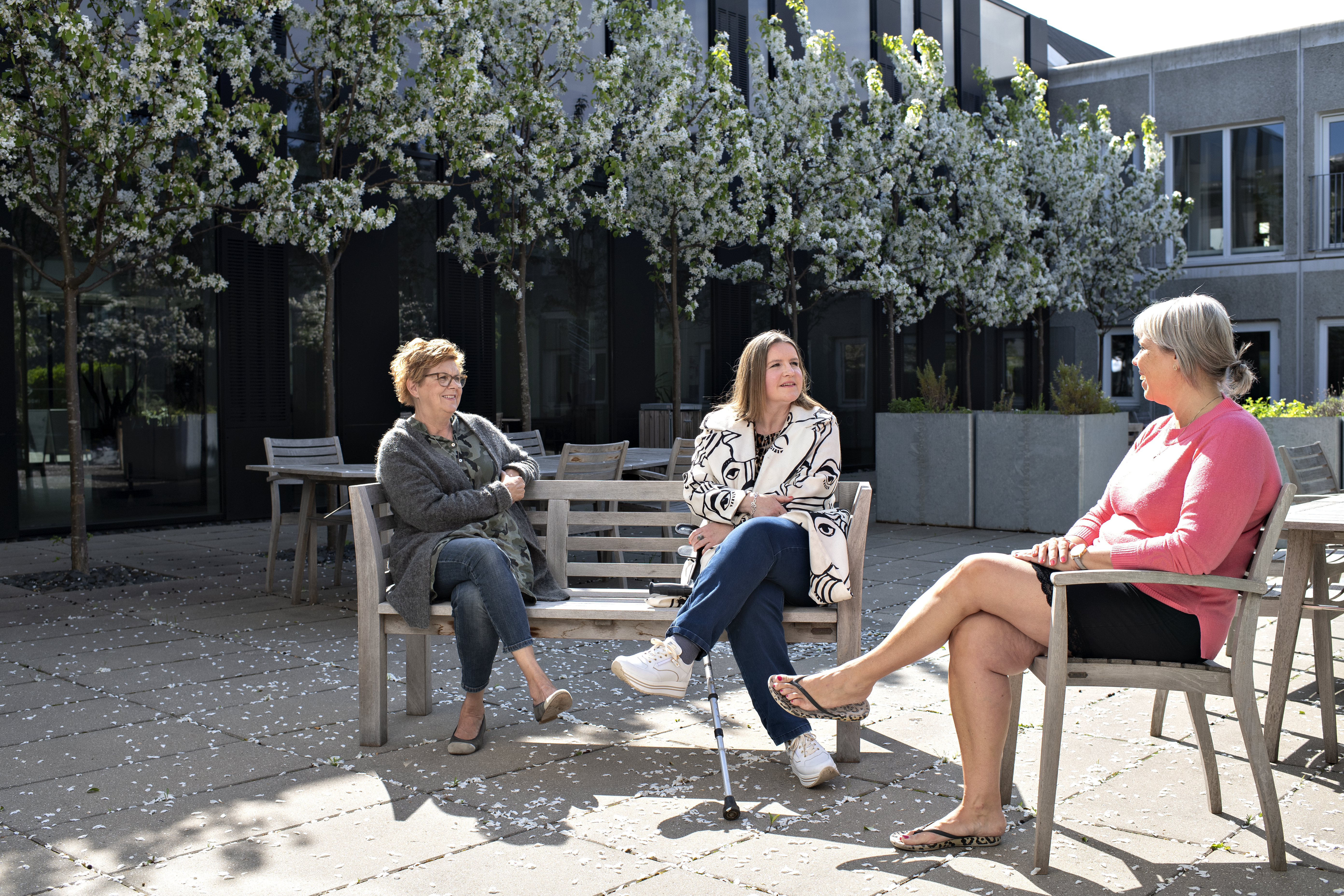 Tre personer sidder på en bænk og taler ved SpecialHospitalet i Rødovre.