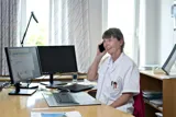 Laege sidder ved bord og snakker i telefon
