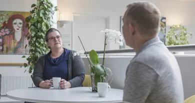 En mand og en kvinde sidder rundt om et bord og har en dialog