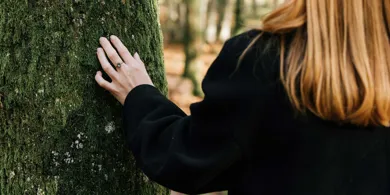 Kvinde i naturen og roer et trae