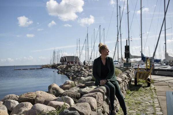 En kvinde sidder på nogle sten ved havnen i Dragør.