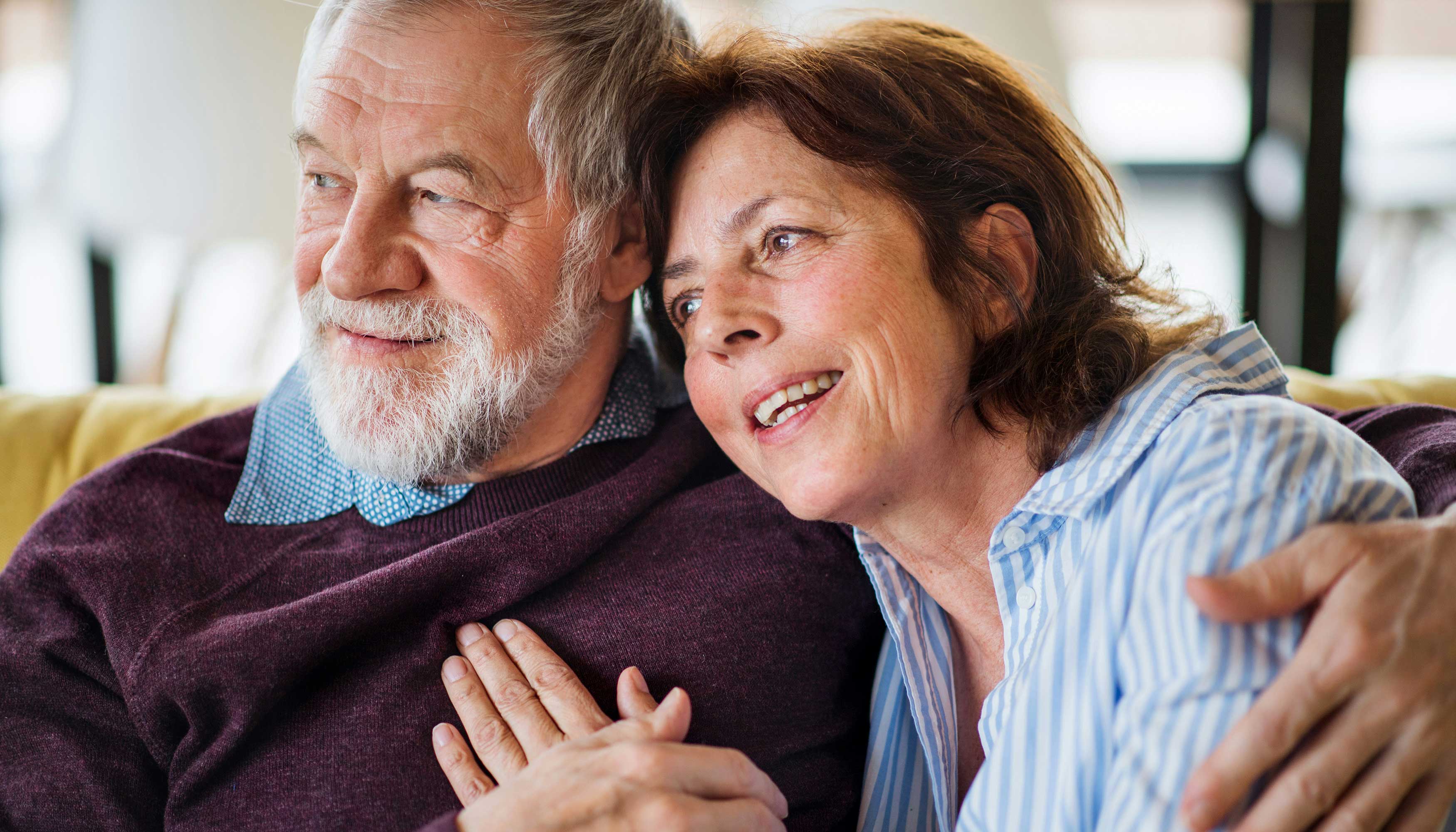Mand og kvinde sidder tæt sammen i sofa.