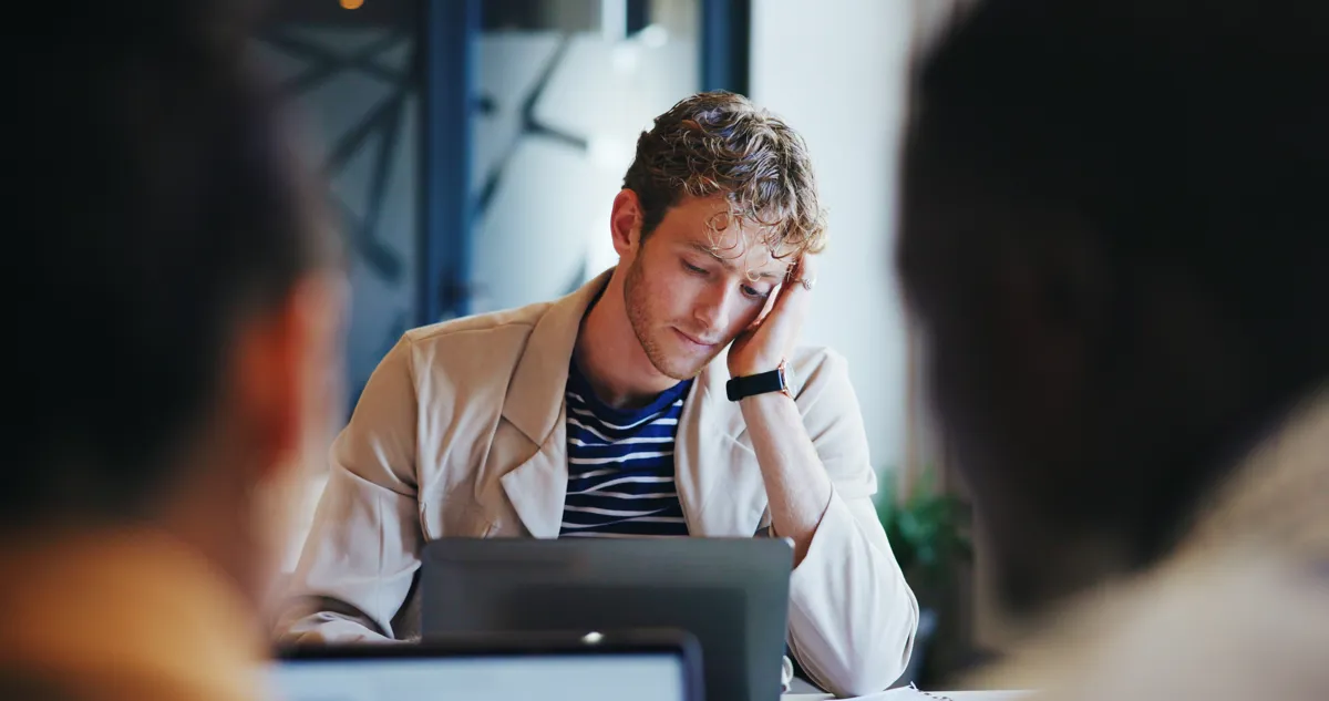 Ung mand sidder foran en computer med haanden til hovedet.