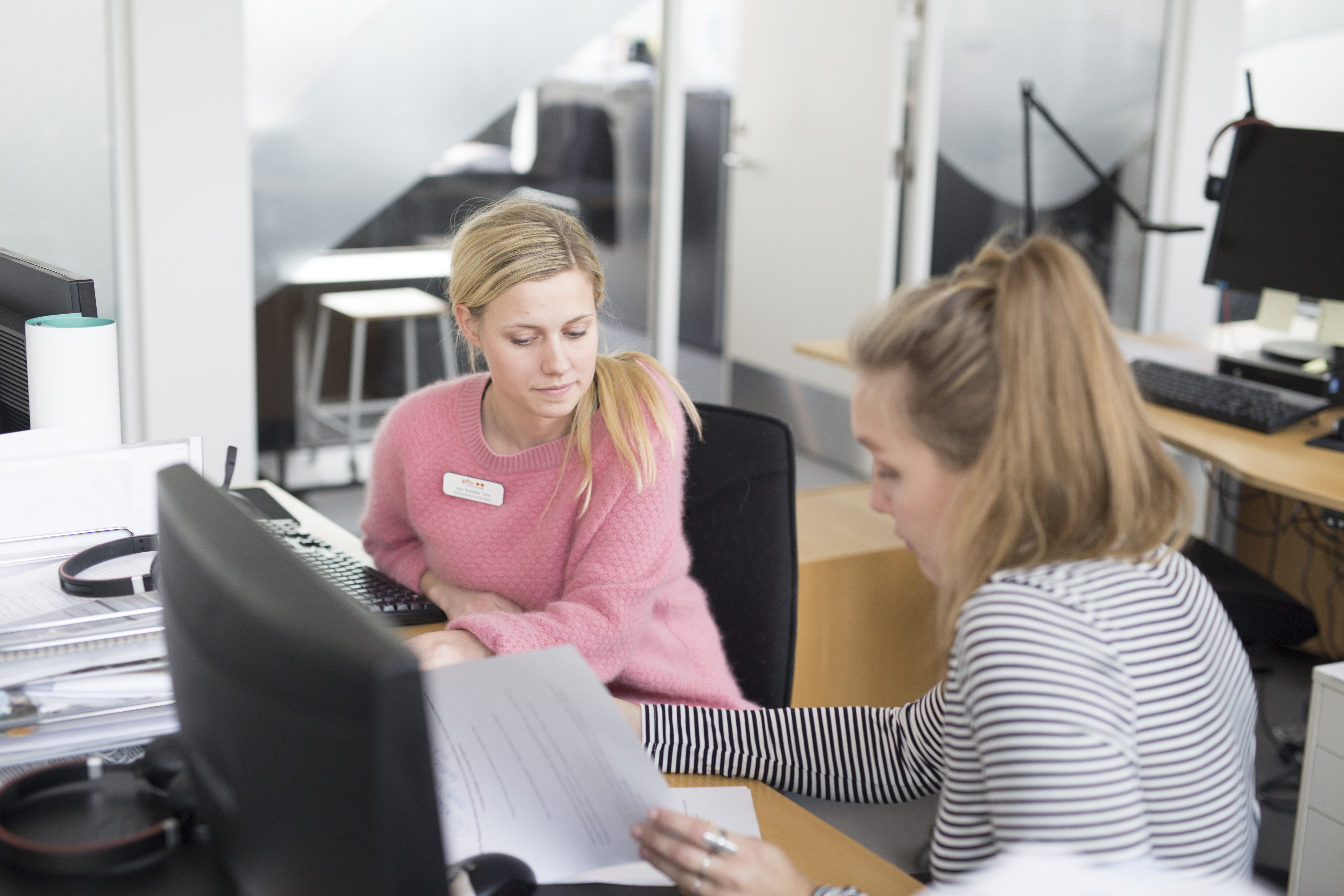 To medarbejdere sidder og taler sammen, imens de kigger papirer igennem.